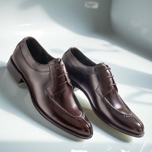 Könnte beinhalten: Ein Paar dunkelbraune Lederschuhe im klassischen Design. Die Schuhe haben eine spitze Zehenpartie und einen Schnürverschluss. Die polierte Oberfläche verleiht ihnen ein formelles Aussehen. Geeignet für besondere Anlässe.