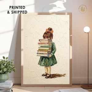 May include: A framed art print featuring a young girl in a green dress carrying a stack of books. The girl has brown hair and a bow. The background is textured with a neutral color. The text "PRINTED & SHIPPED" is in the upper left corner.