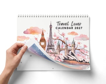 Pode incluir: Um calendário de parede 2027 intitulado Travel Lover com ilustrações em aguarela de monumentos mundiais, incluindo a Torre Eiffel, o Big Ben e a Ópera de Sydney, com flores de cerejeira cor-de-rosa e nuvens suaves num fundo branco.