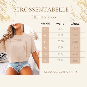 May include: A beige t-shirt size chart for Gildan 5000. The chart lists sizes S through 3XL with corresponding width and length measurements in centimeters. A diagram on the left illustrates how to measure width and length on a beige t-shirt.