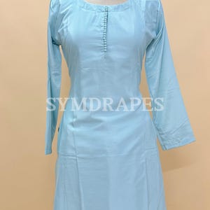 May include: Light blue Kurti and palazzo set. The long-sleeved Kurti features a round neckline and a buttoned placket. The palazzo pants are wide-legged. The text "SYMDRARES" is visible on the Kurti. The outfit is displayed on a mannequin.
