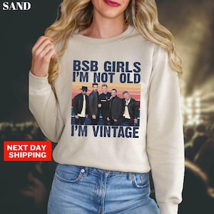 May include: Beige sweatshirt with the text "BSB GIRLS I'M NOT OLD I'M VINTAGE" in blue and white. The graphic includes a photo of the Backstreet Boys. The sweatshirt is a crew neck style.