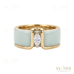 Könnte beinhalten: Ein goldener Ring mit einem hellgrünen Band und einem Diamanten im Marquiseschliff. Der Ring hat ein modernes Design mit einer Goldeinfassung, die den Diamanten einfasst und das Band akzentuiert. Der Ring ist ein Schmuckstück.