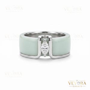 Könnte beinhalten: Breiter Bandring mit hellgrüner Emaille-Oberfläche und einem Diamanten im Marquise-Schliff. Der Ring hat eine silberfarbene Metalleinfassung. Der Ring ist ein Schmuckstück.