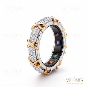 Könnte beinhalten: Ein Ring aus Silber und Gold mit einem pavé-gefassten Diamant-Außenring und goldenen X-förmigen Akzenten. Das Innenband ist schwarz und enthält vier quadratisch geschliffene Edelsteine in Rot, Blau, Grün und Gelb, die in Abständen eingesetzt sind.