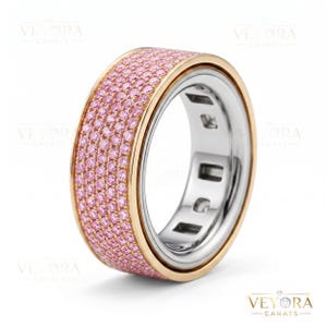 Puede incluir: Un anillo de oro y plata con una banda de piedras preciosas rosas. El anillo tiene una banda ancha con una fila de piedras preciosas rosas engastadas en un engaste de canal. El anillo tiene un borde dorado y un interior plateado.