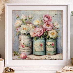 Può includere: Un'opera d'arte a punto croce incorniciata con tre contenitori in metallo vintage pieni di peonie rosa e bianche. I contenitori presentano dettagli floreali e testuali. L'opera è ambientata su uno sfondo azzurro.