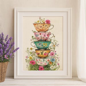 May include: A framed cross-stitch embroidery featuring a vertical stack of five decorative teacups in shades of orange, pink, teal, yellow, and white, each adorned with floral patterns and surrounded by colorful wildflowers on a grid fabric.