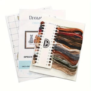 May include: A cross-stitch kit featuring a cat design, including a printed pattern, aida cloth, and a color chart with DMC threads. The kit includes a variety of thread colors, and the pattern is labeled "Dream Cross". The kit is labeled "DPD230".