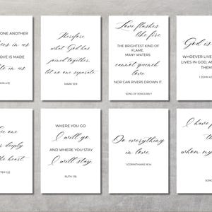 May include: Eight white rectangular cards featuring inspirational quotes in elegant black script. The quotes include phrases such as "God is love" and "Do everything in love." The cards are arranged on a light grey surface.