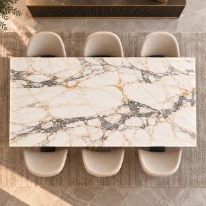 May include: A rectangular dining table with a white marble top featuring prominent grey and gold veining. Six upholstered chairs with curved backrests in a light beige fabric are arranged around the table in a symmetrical layout.