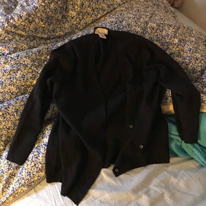 May include: A black cardigan with a single button closure. The cardigan has a 'LOFT' label on the inside.