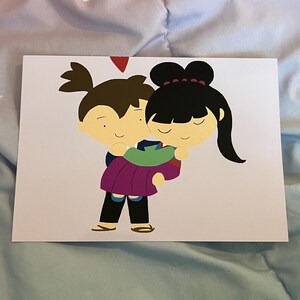 May include: A greeting card featuring a cartoon illustration of a couple embracing. The man is carrying the woman, both with closed eyes and smiling. The man wears a blue and purple outfit, and the woman wears a black hair bun with a red hair tie. A red heart is above them.