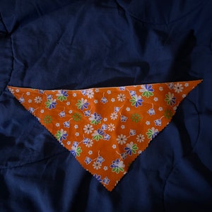 May include: A triangular orange bandana with a white and blue floral pattern.