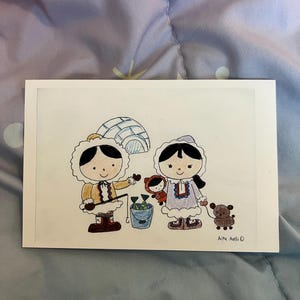 May include: A hand-drawn illustration on white paper depicts two figures in winter clothing, an igloo, and a small bucket of fish. A small child and a teddy bear are also present. The artwork is signed "Aika Aelli".