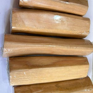 Pu&ograve; includere: Diversi blocchi di legno rettangolari marrone chiaro avvolti in plastica trasparente. I blocchi presentano una venatura naturale del legno e un aspetto liscio e lucido. Il legno &egrave; di colore marrone chiaro.
