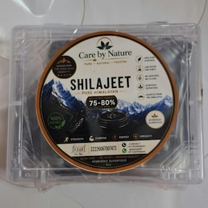 Pode incluir: Um recipiente retangular de plástico transparente com um rótulo circular para Care by Nature Shilajeet. O rótulo apresenta um gráfico de montanha, o texto Shilajeet Pure Himalayan, 75-80% ácido fúlvico e ícones de força, energia e imunidade.
