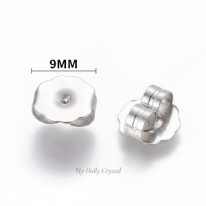 Pode incluir: Duas costas de brincos prateadas, cada uma com formato de flor. Uma vista de frente, a outra de lado. O texto "9MM" indica uma medida de 9 milímetros.