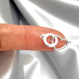 May include: A silver-colored clasp with a heart-shaped design and a circular clasp. The clasp is small and delicate, with the text "My Daily Crystal" visible in the background.