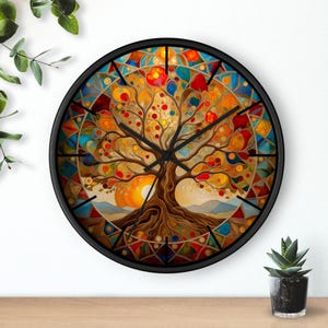 Puede incluir: Un reloj de pared redondo con marco negro. La esfera del reloj presenta un diseño de árbol colorido con una vibrante mezcla de tonos naranja, rojo, amarillo y azul. Las ramas del árbol están llenas de orbes coloridos, y el fondo representa una puesta de sol.