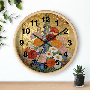 Puede incluir: Reloj de pared redondo con marco de madera clara. La esfera del reloj presenta un arreglo floral de amapolas rojas, flores naranjas y rosas y margaritas blancas sobre un fondo dorado. Los números negros marcan las horas.