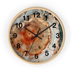 May include: A round wall clock with a light wood frame. The clock face features a detailed cross-section of a tree trunk, showcasing concentric rings in shades of brown, orange, and tan. Black hands indicate the time, with black numerals marking the hours.