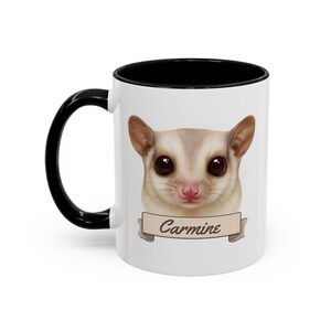Peut inclure: Mug en céramique blanche avec une anse et un intérieur noirs. La tasse présente une illustration détaillée d'un planeur de sucre avec de grands yeux bruns et le nom "Carmine" sur une bannière. Un cadeau charmant et unique.