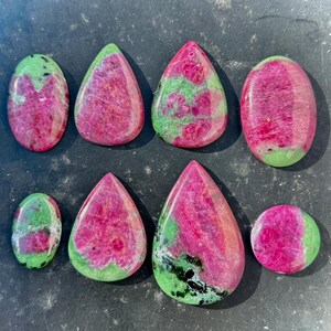 Peut inclure: Huit pierres précieuses de rubis zoïsite polies de différentes formes, dont ovales, en goutte et rondes. Les pierres présentent un mélange vibrant de couleurs rose, vert et noir, mettant en valeur les motifs et textures naturels. Idéal pour la création de bijoux.