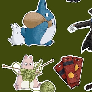K&ouml;nnte beinhalten: Eine Sammlung von Cartoon-Aufklebern mit Charakteren aus einem beliebten Animationsfilm. Die Aufkleber zeigen ein blaues Wesen mit einer Tasche, ein wei&szlig;es Wesen, einen rosa Hamster, der mit gr&uuml;ner Wolle strickt, sowie rote und schwarze Karten.