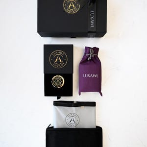 May include: A white ceramic mug with a black handle and the text "But First, Coffee" in a black, bold font. The mug is on a white surface. The mug is approximately 10 cm tall.