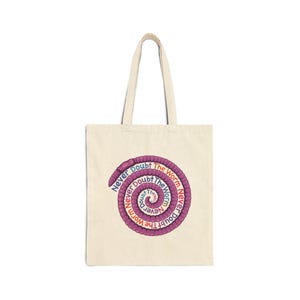 May include: Cream-colored tote bag with a spiral design featuring the text "Never Doubt The Worm" in a circular pattern. The spiral is made of a purple, textured design. The bag has a simple, rectangular shape with matching handles.