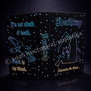 Peut inclure: Un livre noir avec le titre "Deathitrap" et le nom de l'auteur, Alexandra St. Pierre, en lettrage irisé. La couverture présente un corbeau, le texte "I'm not afraid of death. Death is my friend," et une silhouette d'une figure avec une faux.