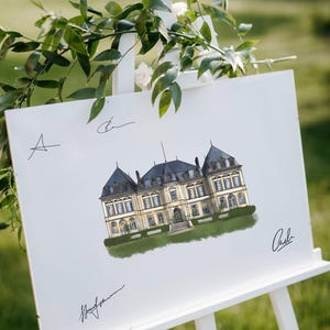 May include: A white sign on an easel displays a detailed illustration of a stately building with a dark gray roof and light-colored walls. Green foliage and signatures are also visible. The sign is set against a blurred green background.