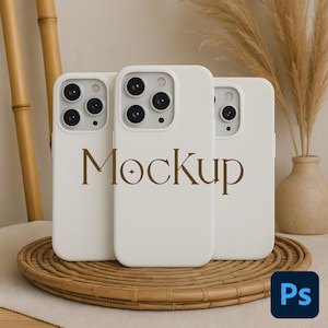 Könnte beinhalten: Drei weiße Handyhüllen mit Kameraausschnitten sind auf einem geflochtenen Tablett angeordnet. Das Wort "Mockup" ist braun auf der mittleren Hülle aufgedruckt. Der Hintergrund umfasst Bambusstiele, Pampasgras und eine Vase.