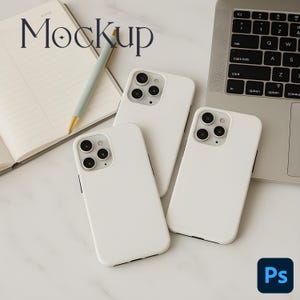 Op de afbeelding: Drie witte smartphones met zwarte cameralenzen zijn gerangschikt op een marmeren oppervlak, in de buurt van een laptop en een notitieboek met een pen. Het woord "Mockup" is geschreven in een stijlvol lettertype. Een blauw en zwart "Ps"-logo staat in de rechter benedenhoek.