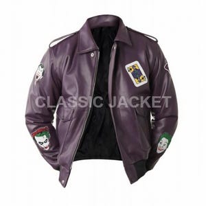 Può includere: Giacca in pelle viola con fodera nera e chiusura a zip. La giacca presenta toppe di un personaggio con i capelli verdi e una carta da gioco. Il testo "CLASSIC JACKET" è stampato sulla giacca.