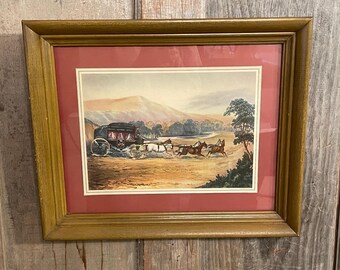 May include: A framed print featuring a dark horse-drawn carriage traveling across a landscape with rolling hills and a tree. The artwork is enclosed in a wooden frame with a deep red mat border, showcasing a scene of travel in a rural setting.