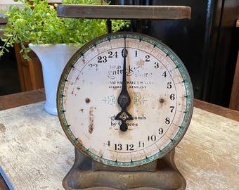 May include: A vintage Old Kentucky Home mechanical scale with a weathered metal finish, a circular white dial featuring black numerals from 0 to 24, a central black pointer, and text indicating a 25-pound capacity by ounces.