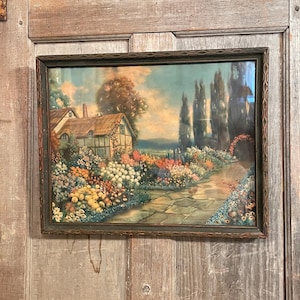 May include: Framed vintage landscape print featuring a cottage with a thatched roof, surrounded by a vibrant garden filled with colorful flowers. A stone path leads through the garden. The frame is dark green.
