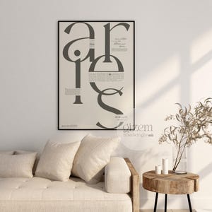 Könnte beinhalten: Ein gerahmter Kunstdruck mit dem Wort "are" in großen, stilisierten Buchstaben. Der Druck hat eine neutrale Farbpalette mit Text und einem schwarzen Rahmen. Der Druck hängt über einem beigen Sofa mit Kissen.