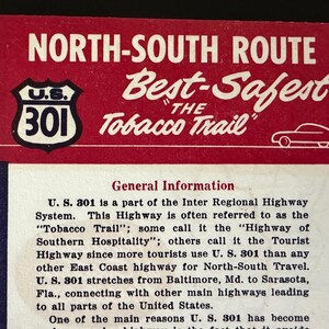 May include: A rectangular informational card with a red header featuring the text NORTH-SOUTH ROUTE, Best-Safest THE Tobacco Trail, a U.S. 301 highway shield icon, and a white car outline. The lower section contains printed text about U.S. 301.