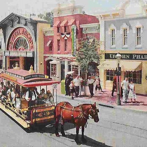 May include: A red and white horse-drawn trolley car travels down a street lined with colourful buildings. The buildings have signs that read "Crystal Arcade" and "Upjohn Pharmacy". There are people walking on the pavement and balloons in the air.