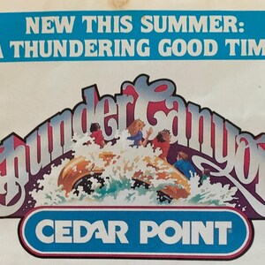 Może przedstawiać: Zabytkowa reklama parku rozrywki Cedar Point. Obrazek przedstawia słowa "New This Summer: A Thundering Good Time!" nad grafiką wodnej przejażdżki o nazwie Thunder Canyon. Logo Cedar Point znajduje się na dole.