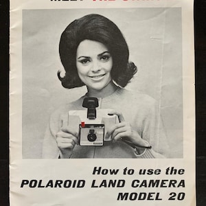 May include: Vintage black and white advertisement featuring a woman holding a Polaroid Land Camera Model 20. The text reads "Meet the Swinger" in red and "How to use the Polaroid Land Camera Model 20". The woman is smiling.