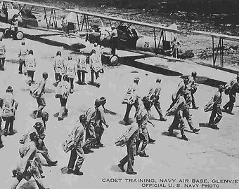May include: Black and white photo of a group of men in uniform walking past a line of biplanes. The photo is captioned "CADET TRAINING, NAVY AIR BASE, GLENVIEW, ILL. OFFICIAL U. S. NAVY PHOTO."