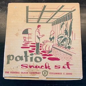 Puede incluir: Una caja de cartón vintage para un "Patio Snack Set" con una ilustración retro de una pareja en un patio. La caja presenta detalles en rojo y verde, con el texto "The Federal Glass Company, Columbus 7, Ohio."