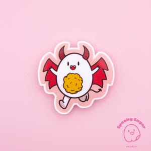 May include: A sticker featuring a cartoon devil with red wings, horns, and a tail. The devil has a white body, a yellow belly, and is running. The sticker has a pink border and is on a pink background. The text "Spooky Sugar studio" is in the bottom right corner.