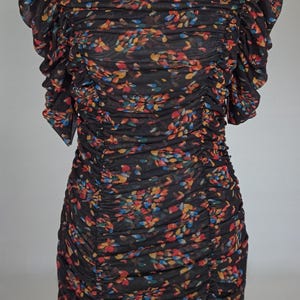 May include: A black, floral-print dress with a round neckline and short, ruffled sleeves. The dress features a ruched bodice and skirt, with a pattern of colorful flowers in shades of red, blue, and yellow.