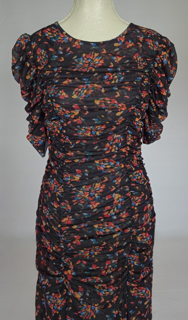 May include: A black, floral-print dress with a round neckline and short, ruffled sleeves. The dress features a ruched bodice and skirt, with a pattern of colorful flowers in shades of red, blue, and yellow.