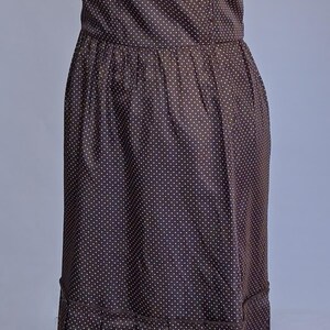 May include: A brown strapless dress with a white polka dot pattern. The dress features a fitted bodice, a gathered waist, and a pleated skirt. The dress is displayed on a mannequin.